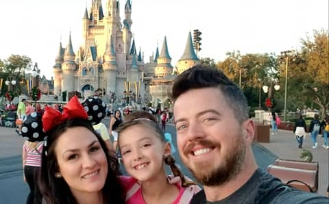 Mom, dad and daughter in front of Disney Castle