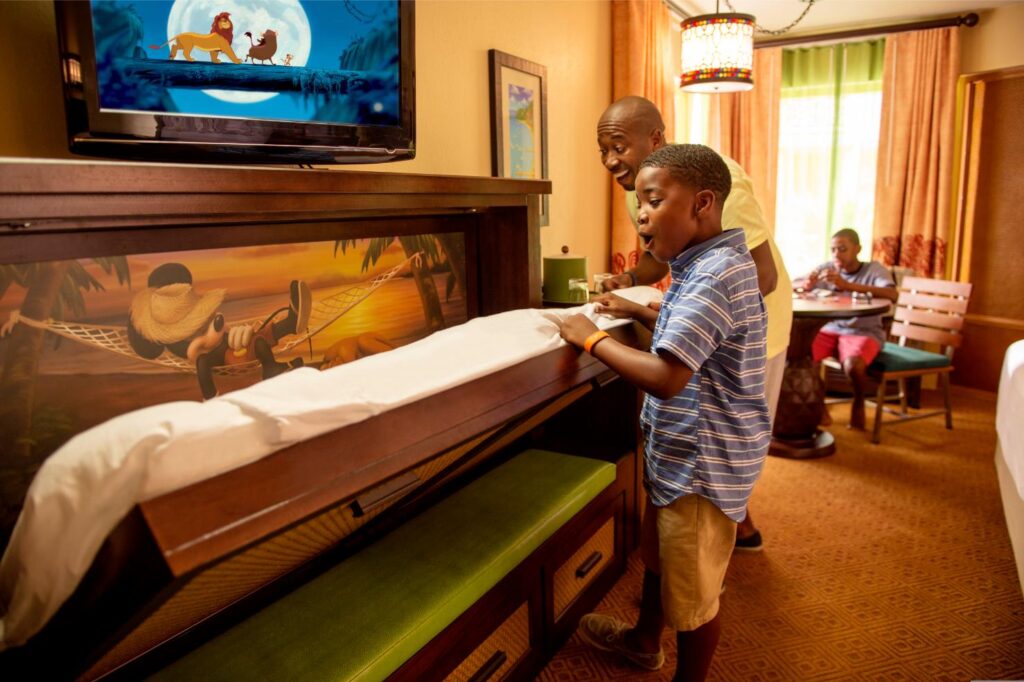Dad and two boys pulling down the fold away bed in a Disney Caribbean Beach Resort room