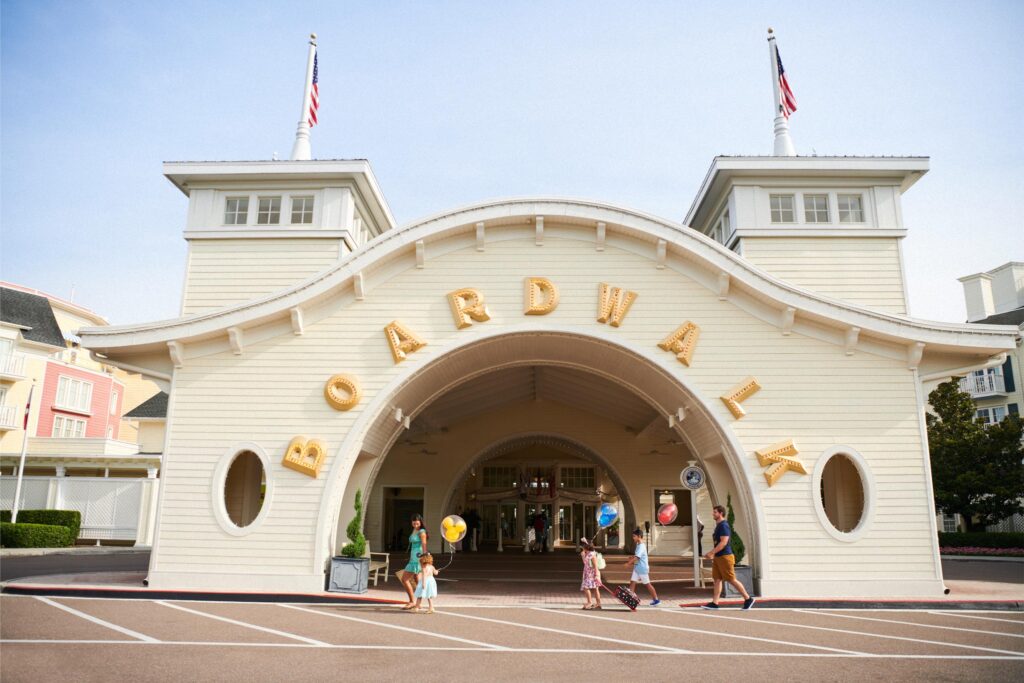 Family with balloons and a rolling suitcase at the entrance of Disney BoardWalk Inn