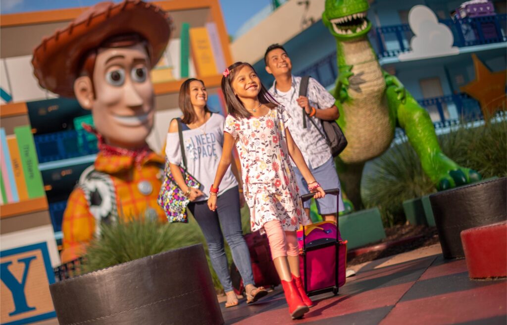 Family with a rolling suitcase walking through the Toy Story courtyard at Disney All-Star Movies Resort