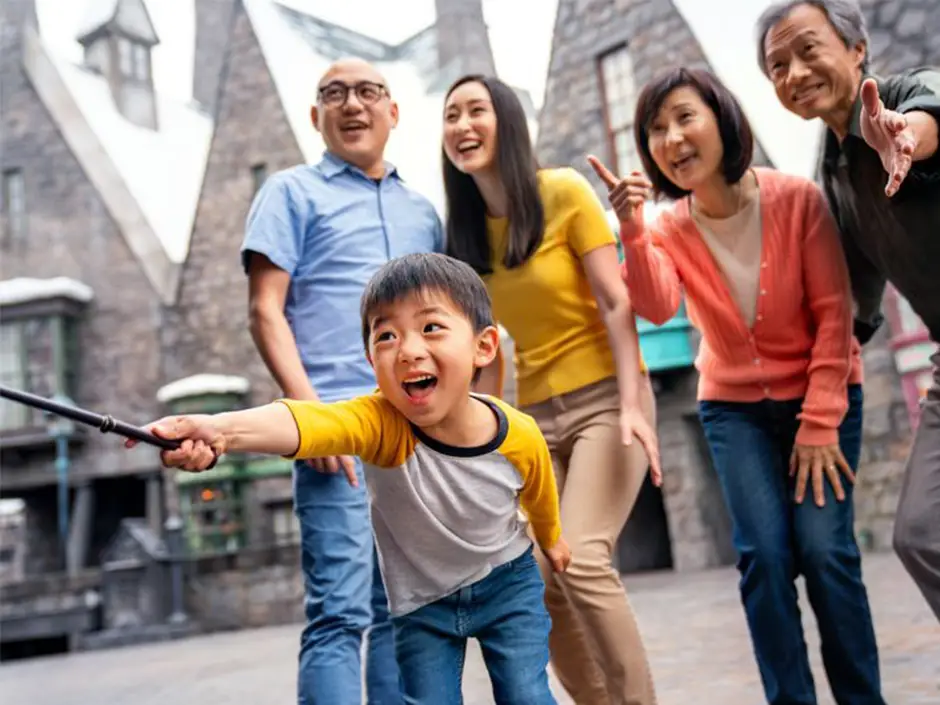 Universal Studios Hollywood the Wizarding World of Harry Potter - Favorite Grampy Travels a Smiling Boy Holds a Wand and Poses Playfully with His Family in Front of Snowy Rooftops at Universal Studios Hollywood, Making Memories That Prove a Buy a Day Get a 2nd Day Free Ticket is Truly Ticket Worth It. - Favorite Grampy Travels