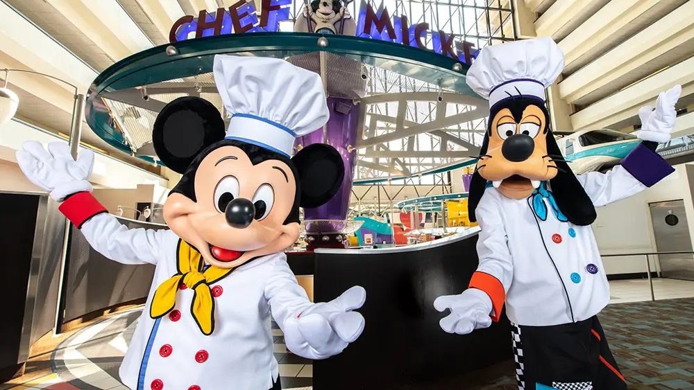 Mickey Mouse and Goofy, Both Dressed As Chefs, Stand with Arms Outstretched and Smiling Faces in Front of the Chef Mickey’s Restaurant Entrance at Bay Lake Tower, One of the Disney World Deluxe Resorts. - Favorite Grampy Travels