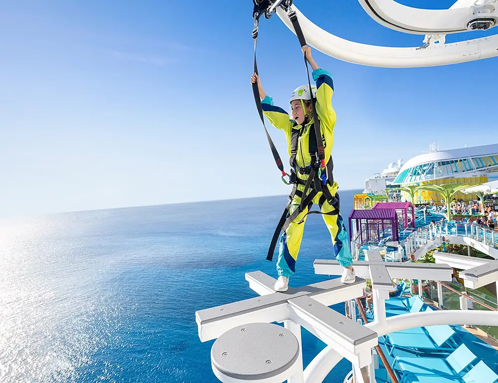a Person Wearing a Harness and Safety Gear Walks on a Suspended Obstacle Course Above the Ocean Aboard the Star of the Seas, Enjoying an Unforgettable Family Cruise with Clear Blue Sky and Sea in the Background—a True Cruise Experience. - Favorite Grampy Travels