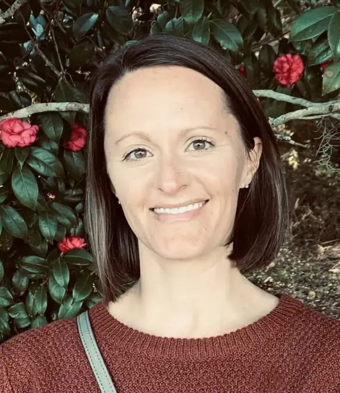Headshot of Kati Petite, a Travel Agent with Favorite Grampy Travels. She is a Woman with Straight Brown Hair and a Maroon Sweater. She Smiles in Front of a Leafy Bush with Small Pink Flowers. - Favorite Grampy Travels - Favorite Grampy Travels 2026