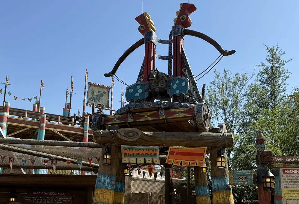 Entrance to an Islands of Adventure Ride, Featuring a Large, Colorful Viking-style Catapult with Shields and Dragon Motifs. Festive Flags and Signs Decorate the Area Under a Clear Blue Sky—express Pass Available for Quicker Access. - Favorite Grampy Travels - Favorite Grampy Travels 2026