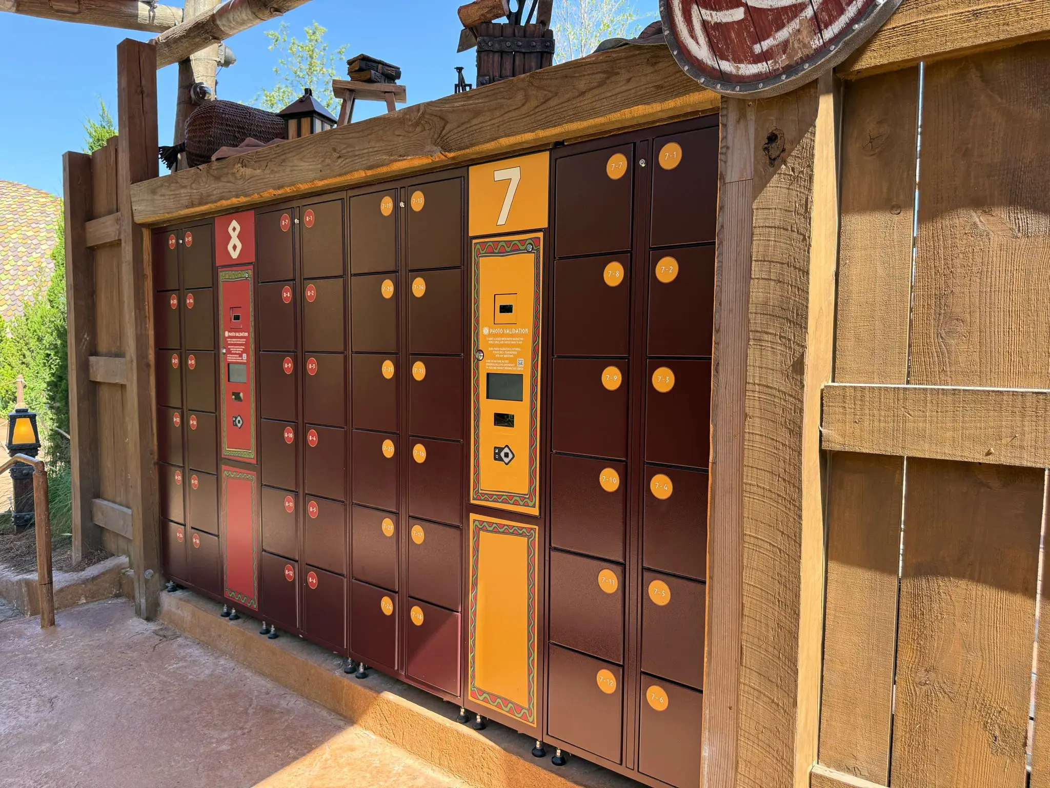 a Set of Universal Orlando Locker Units with Brown and Orange Doors, Labeled 7 and 8, is Mounted Against a Wooden Fence in a Sunny Area—perfect for Storing Your Belongings During Your Epic Universe Adventure. - Favorite Grampy Travels - Favorite Grampy Travels 2026