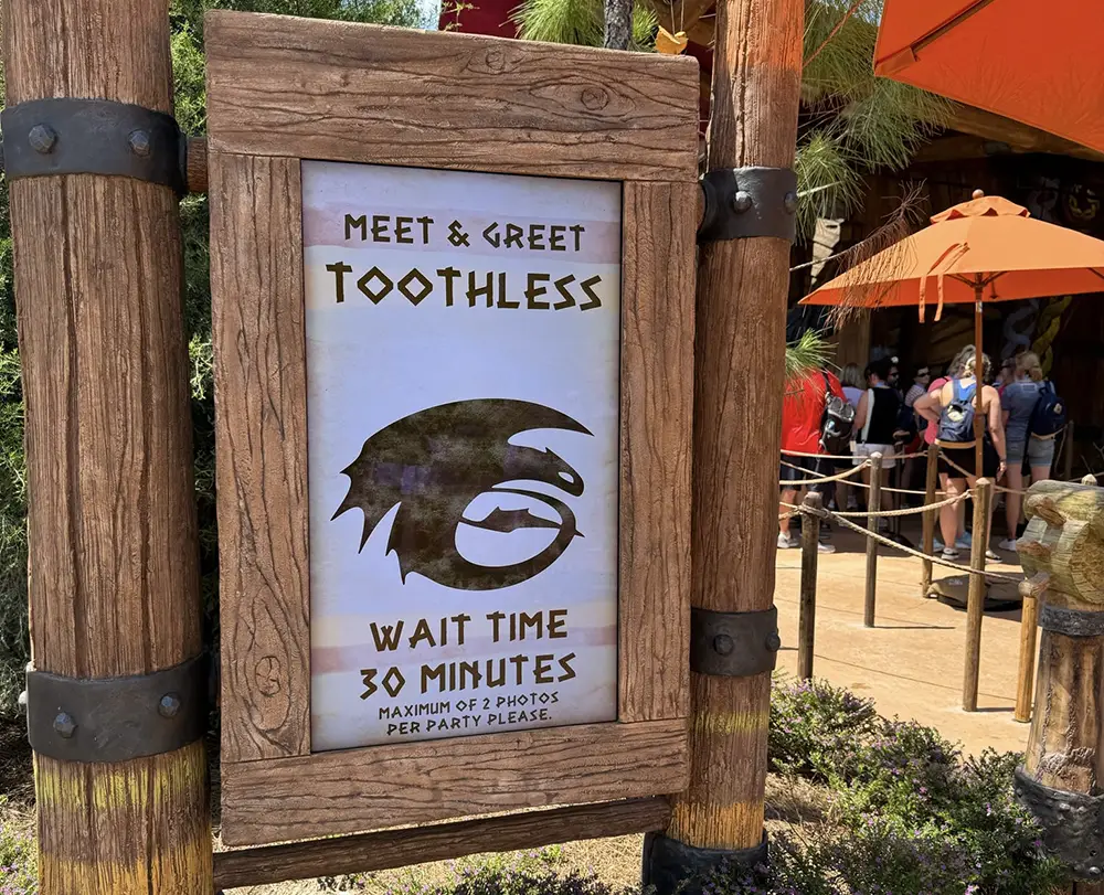 a Sign at Universal Studios Reads Meet & Greet Toothless. Wait Time 30 Minutes. Maximum of 2 Photos Per Party Please, with a Black Silhouette of Toothless’s Face from How to Train Your Dragon. Express Pass Not Accepted for This Experience. - Favorite Grampy Travels - Favorite Grampy Travels 2026