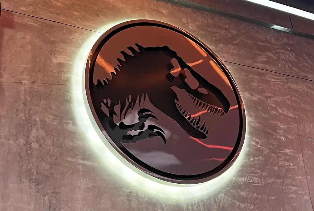 a Round, Illuminated Wall Sign Featuring the Silhouette of a Dinosaur Head with an Open Mouth and Sharp Teeth Against a Textured Gray Background, Inspired by the Thrilling Rides at Universal’s Islands of Adventure. - Favorite Grampy Travels - Favorite Grampy Travels 2026