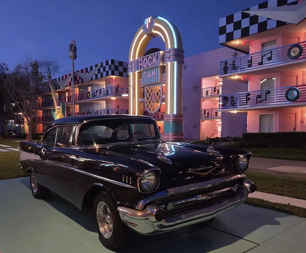 Classic Black 1950s Car Parked on a Retro Neon-lit Motel Lawn, with a Colorful Arch Sign in the Background. - Favorite Grampy Travels 2026