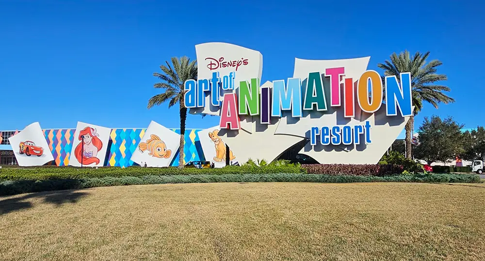 Wdw-disneys-art-of-animation-resort-front-sign - Favorite Grampy Travels Large Colorful Sign for Disney’s Art of Animation Resort, Part of the Walt Disney Resort Tiers, Featuring Bold Letters and Images of Ariel, Nemo, and Lightning Mcqueen with Palm Trees and a Bright Blue Sky in the Background. - Favorite Grampy Travels - Favorite Grampy Travels 2026