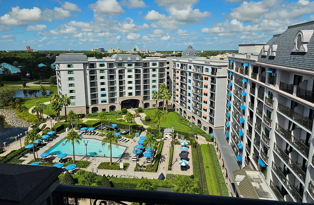 Wdw-riviera-resort-overview-rooftop-balcony - Favorite Grampy Travels a Large, Elegant Hotel with Gray Roofs and Balconies Overlooks a Courtyard Featuring a Blue Outdoor Pool at Disney’s Riviera Resort, Where Sun Loungers, Palm Trees, and Gardens Create a Dreamy Retreat Near the Convenient Skyliner. - Favorite Grampy Travels - Favorite Grampy Travels 2026