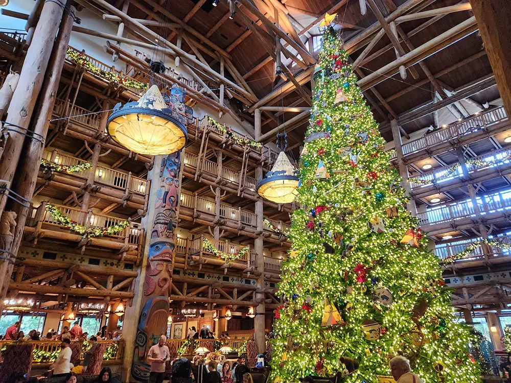 Wdw-wilderness-lodge-christmas-lobby - Favorite Grampy Travels a Large, Brightly Lit Christmas Tree Stands in the Lobby of a Rustic Resort Hotel, Decorated with Ornaments and Surrounded by Balconies with Garlands. Guests Gather Beneath High Ceilings and Warmly Lit Hanging Lamps. - Favorite Grampy Travels - Favorite Grampy Travels 2026