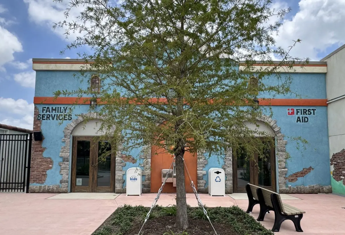 Front View of a Blue Service Building with Family Services and First Aid Signs, a Tree in the Foreground and Benches Nearby. - Favorite Grampy Travels 2026
