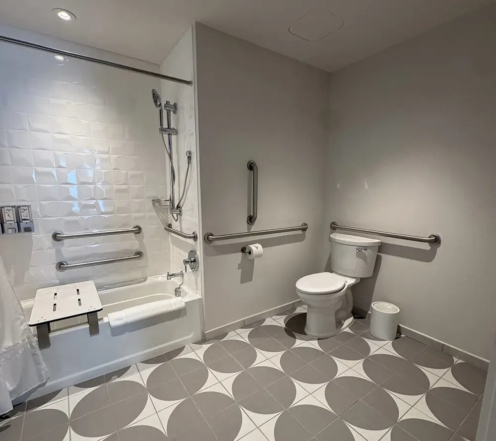 Ukr-hotel-acessible-bathroom - Favorite Grampy Travels Accessible Hotel Bathroom with a Walk-in Bathtub, Foldable Shower Seat, Multiple Grab Bars, Handheld Showerhead, Toilet with Grab Bars, Toilet Paper Holder, and Geometric Patterned Tile Floor. - Favorite Grampy Travels - Favorite Grampy Travels 2026