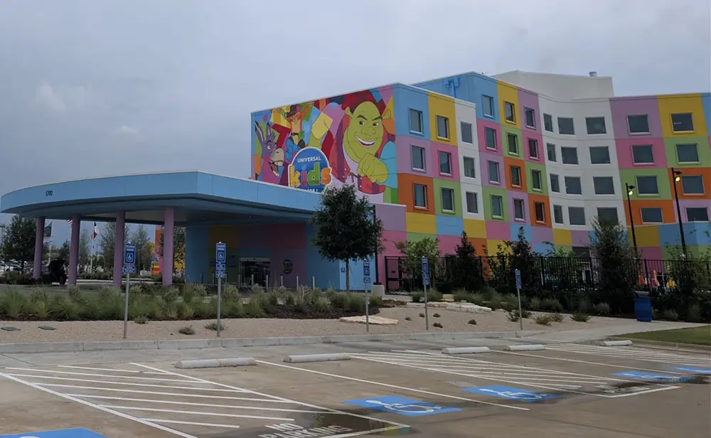 Ukr-hotel-parking-lot - Favorite Grampy Travels a Colorful Hotel Building with a Mural Featuring Animated Characters, Bright Geometric Shapes, and the Word Kids Above the Entrance. the Parking Lot in Front Includes Several Accessible Parking Spaces. - Favorite Grampy Travels - Favorite Grampy Travels 2026