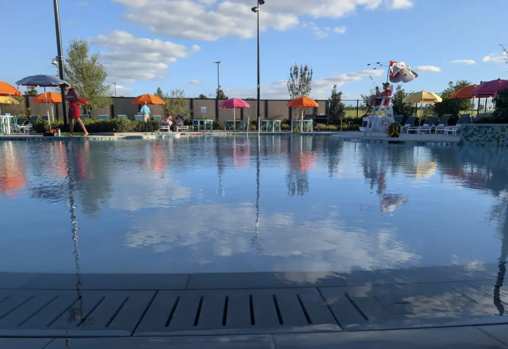 Ukr-hotel-pool - Favorite Grampy Travels a Calm Outdoor Swimming Pool Reflects the Blue Sky and Clouds, Surrounded by Colorful Umbrellas and a Few People Relaxing by the Poolside on a Sunny Day. - Favorite Grampy Travels - Favorite Grampy Travels 2026