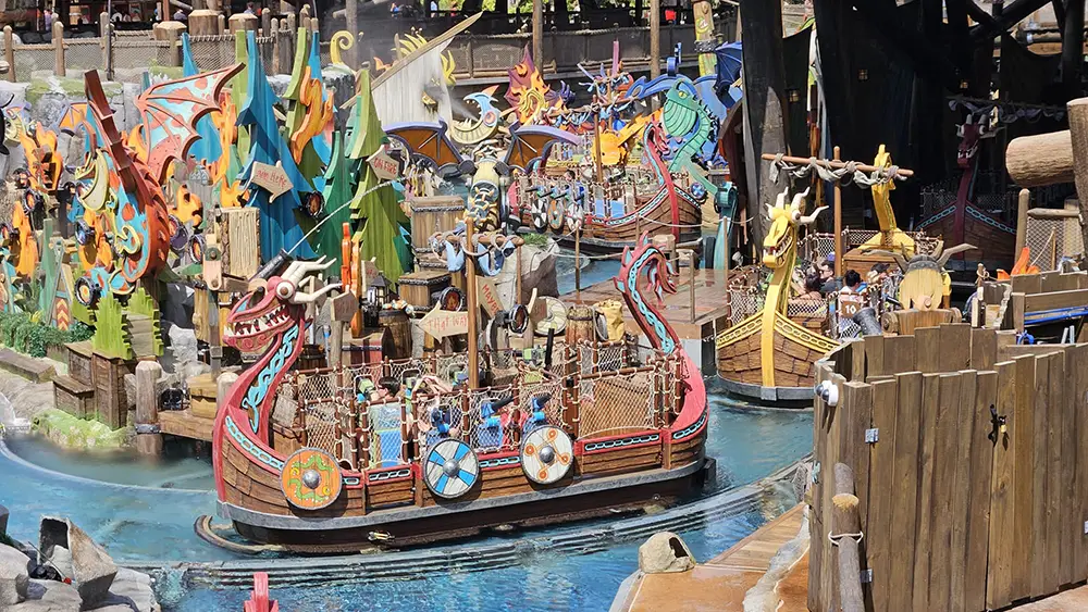 Colorful Viking-themed Boats with Dragon Heads and Shields Carry People Through a Winding Water Ride Surrounded by Vibrant, Playful Decorations in Epic Universe - Favorite Grampy Travels 2026's Isle of Berk, making it one of the park’s most exciting attractions. - Favorite Grampy Travels
