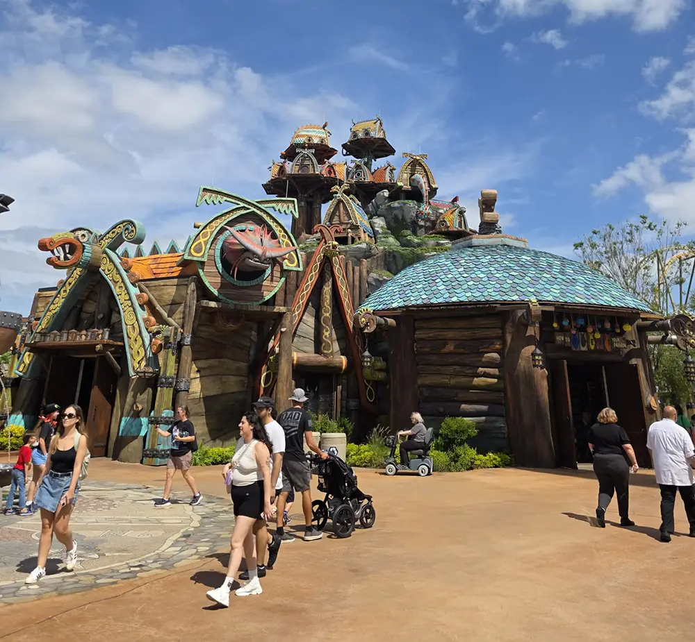 People Walk and Push Strollers Outside a Whimsical, Cartoonish Building with Colorful, Curved Roofs and Wooden Textures, Under a Partly Cloudy Sky. the Building Resembles an Attraction at a Theme Park. - Favorite Grampy Travels - Favorite Grampy Travels 2026