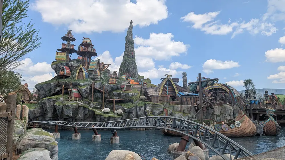 a Whimsical Epic Universe Theme Park Scene Features Viking-style Houses on a Rocky Hill, a Tall Jagged Mountain Peak, a Roller Coaster Track, and a Decorative Boat by Blue Water—a Magical Setting Perfect for Toddlers to Explore Under Partly Cloudy Skies. - Favorite Grampy Travels - Favorite Grampy Travels 2026