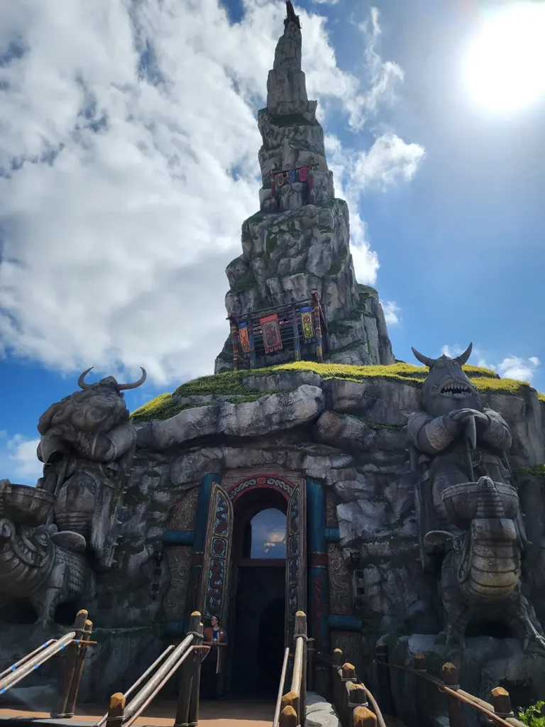 a Towering, Rocky Structure Resembling a Mountain with Large Horned Warrior Statues Flanking Its Entrance, Under a Partly Cloudy Sky. the Entrance is Framed by Colorful, Ornate Designs—hinting at Some of the Best Dining Options in the Epic Universe Restaurants. - Favorite Grampy Travels - Favorite Grampy Travels 2026