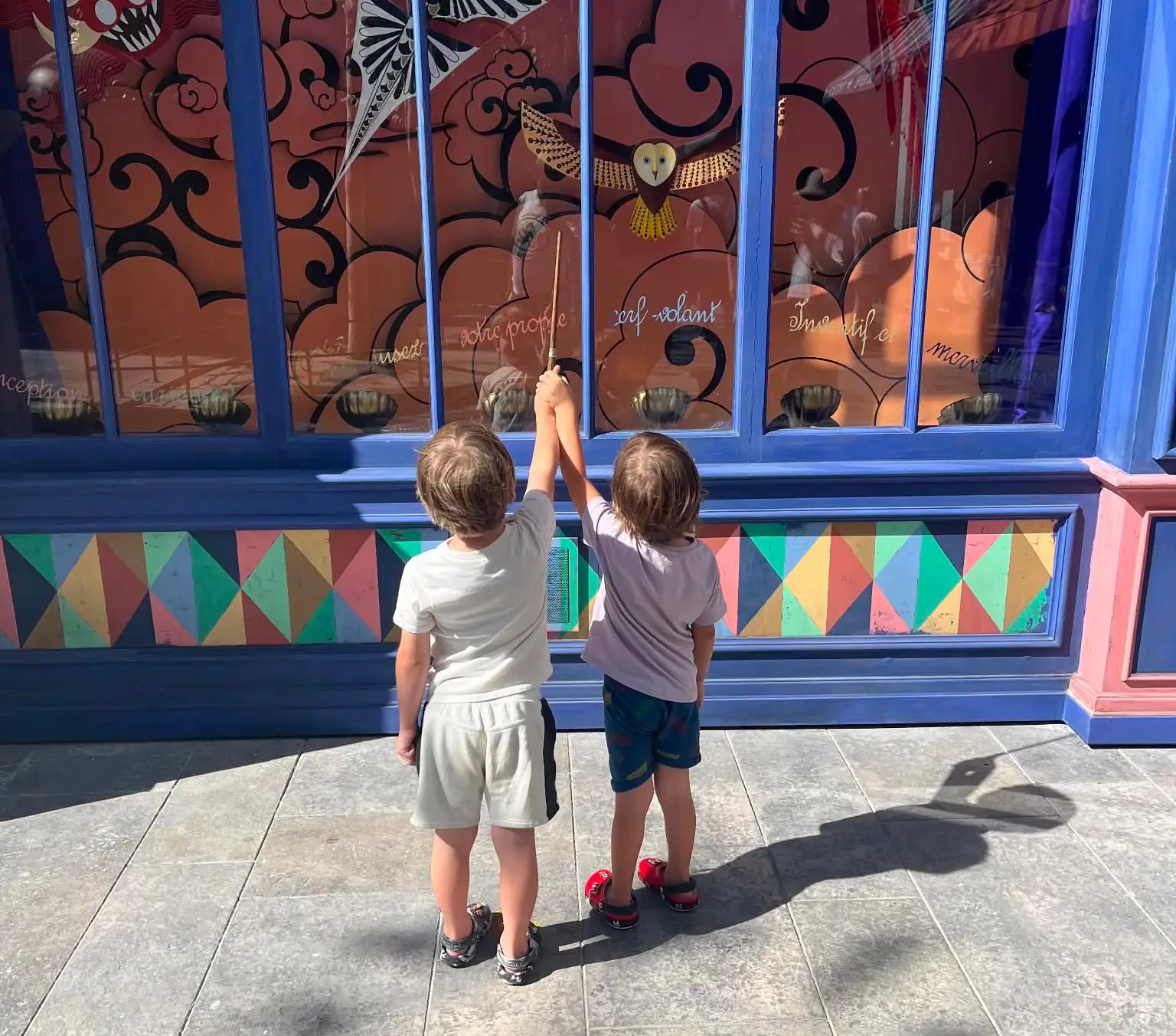 Two Kids Casting Spells with Interactive Wands at a Shop Window in Wizarding Paris at Epic Universe - Favorite Grampy Travels - Favorite Grampy Travels 2026