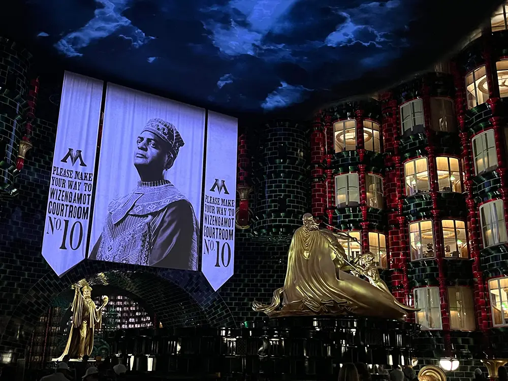 a Large, Dramatic Display Shows a Black-and-white Image of a Wizard in Regal Robes with Text Guiding Visitors—including Kids—toward the Wizengamot Courtroom No. 10 in a Grand, Magical Interior with Golden Statues and Glowing Windows. - Favorite Grampy Travels - Favorite Grampy Travels 2026