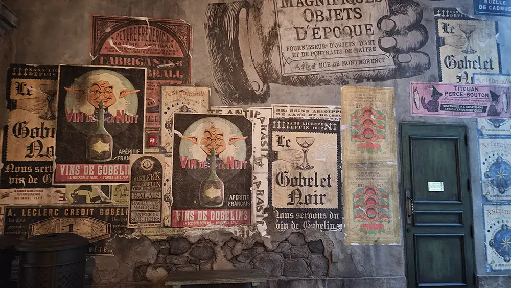 a Stone Wall Covered with Vintage French Posters Featuring Bold Text, Goblin Illustrations, and Ministry of Magic Advertisements. an Old Wooden Door is Visible on the Right Side of the Image. - Favorite Grampy Travels - Favorite Grampy Travels 2026