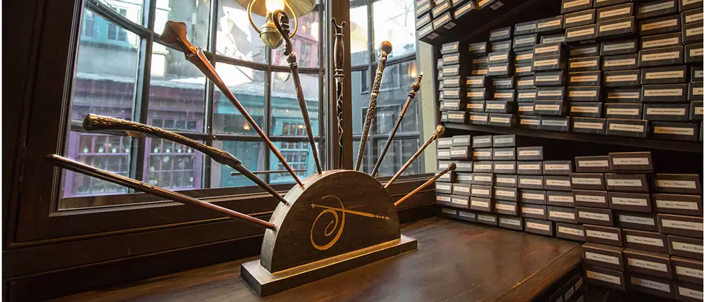 a Display of Ornate Wands Stands on a Wooden Counter in Front of a Window, Surrounded by Shelves Filled with Labeled Wand Boxes, Resembling a Wand Shop from the Harry Potter Universe. - Favorite Grampy Travels - Favorite Grampy Travels 2026