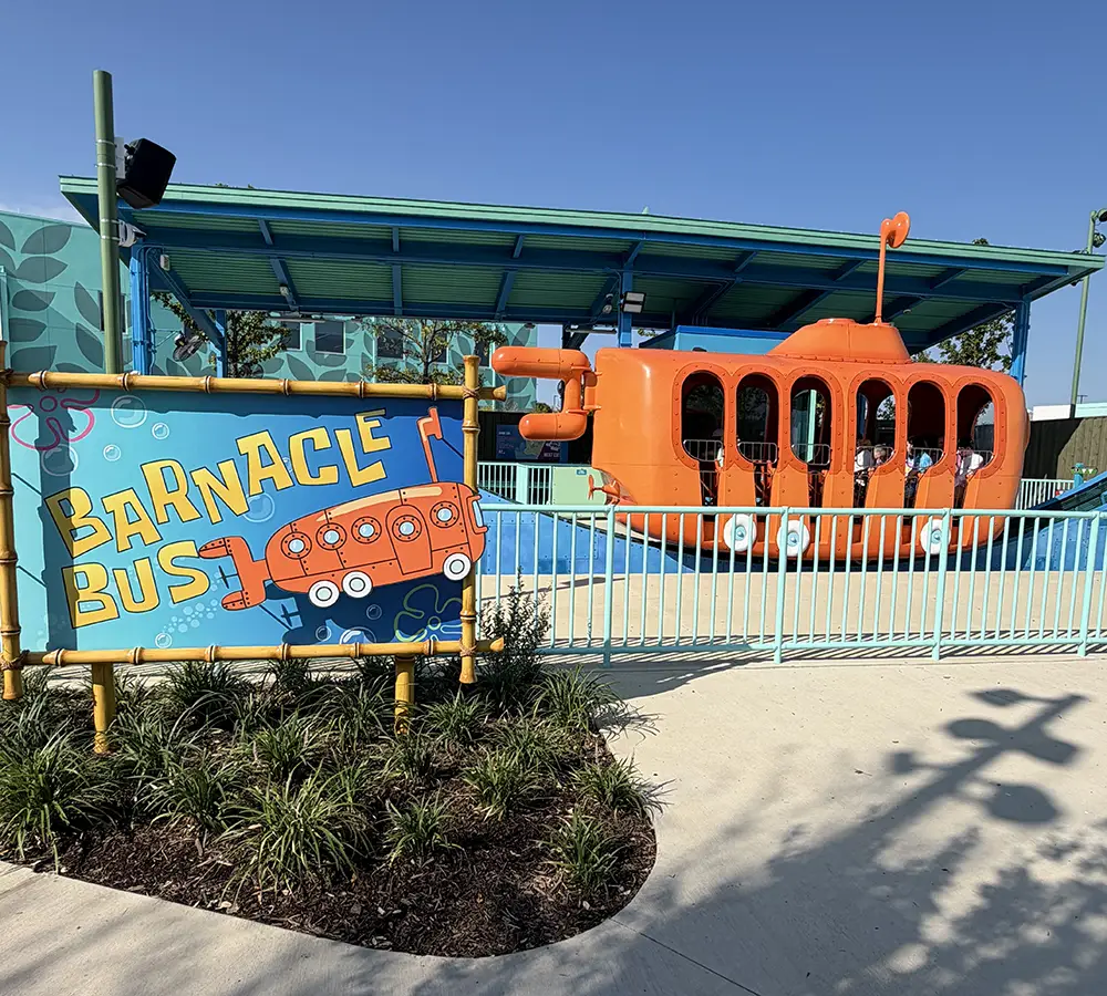 an Orange Submarine-themed Ride Called Barnacle Bus Sits Behind a Colorful Sign with the Same Name, Surrounded by Blue Railings and a Modern, Aquatic-themed Building—one of the Standout Universal Kids Resort Rides Perfect for Families on Their First Day of Adventure. - Favorite Grampy Travels - Favorite Grampy Travels 2026