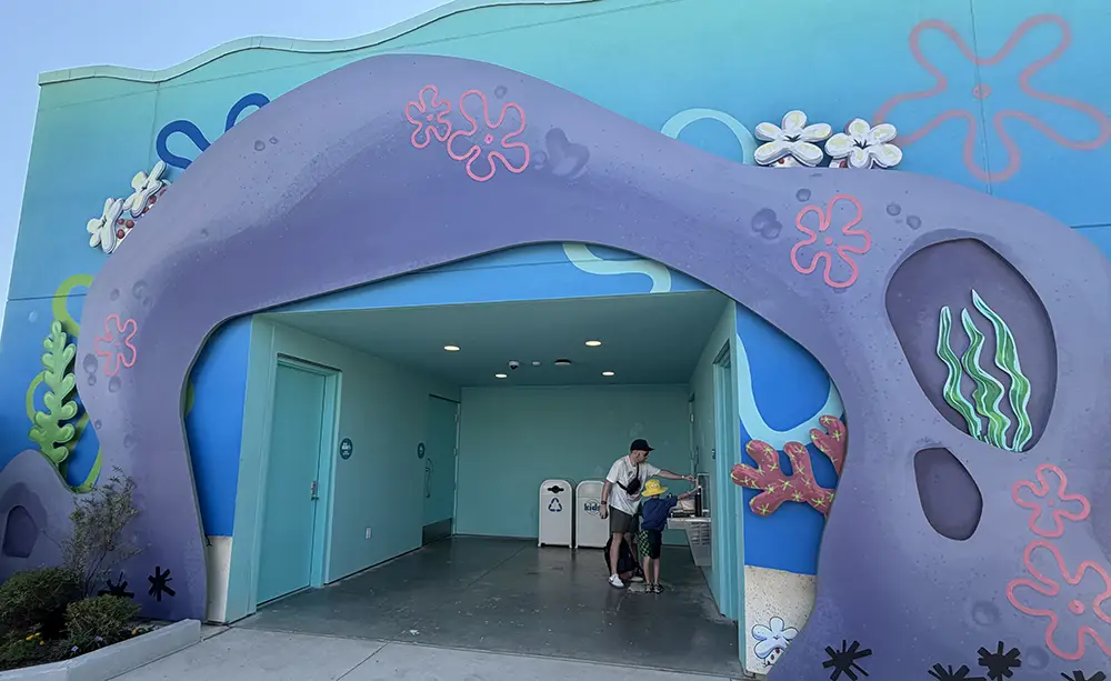 a Person Helps a Child Near the Entrance of a Whimsical Building Decorated with Underwater-themed Designs Like Coral and Bubbles, Inspired by the Cartoon Spongebob Squarepants, on Their First Day Exploring Universal Kids Resort Rides. - Favorite Grampy Travels - Favorite Grampy Travels 2026