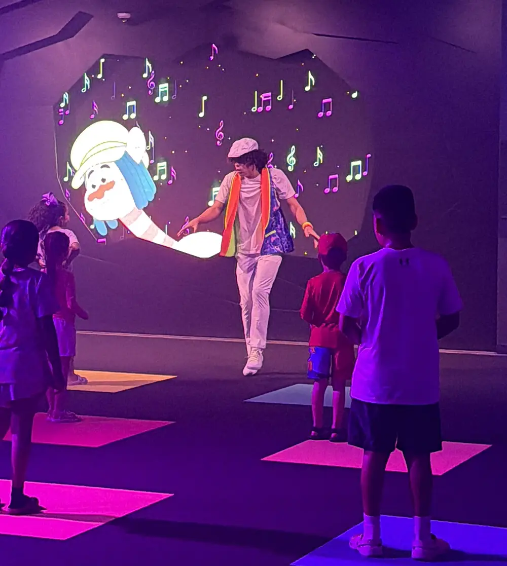 Ukr-trolls-king-trollex-techno-dance-party - Favorite Grampy Travels Performer Dancing on Stage in Front of Children Inside King Trollex Techno Dance Party at Universal Kids Resort, the Room Lit Purple with Projected Graphics on the Wall - Favorite Grampy Travels 2026