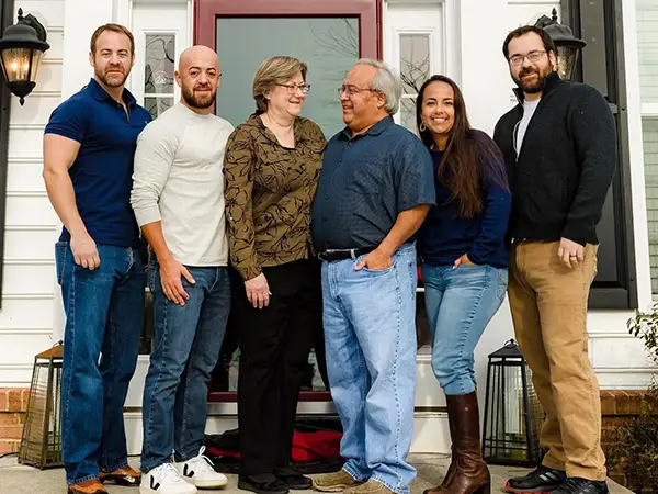 the Oliverez Family. Six People, Four Men and Two Women, Stand Smiling Together in Front of a House Entrance with Glass Double Doors and Outdoor Lanterns on Each Side. - Favorite Grampy Travels - Favorite Grampy Travels 2026 - Favorite Grampy Travels 2026