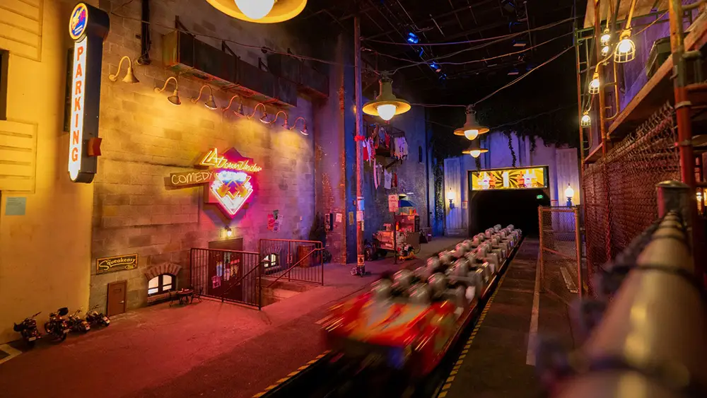 a Roller Coaster Train Speeds Past Neon Signs and City-themed Decor Inside a Dimly Lit Indoor Amusement Park Attraction. - Favorite Grampy Travels - Favorite Grampy Travels 2026