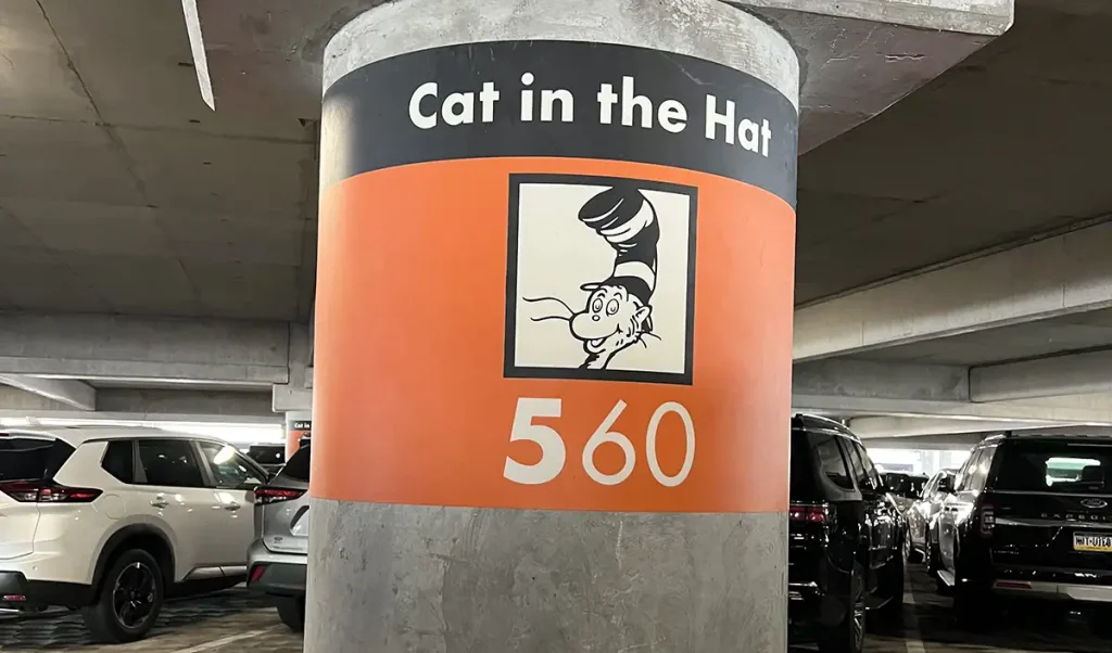 A parking garage column at Universal Orlando Resort labeled Cat in the Hat with a drawing of the character, number 560, and parked cars nearby. - Favorite Grampy Travels