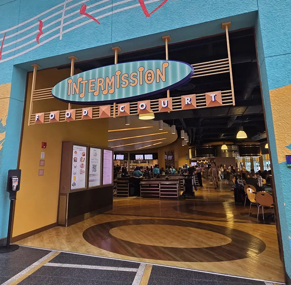 Entrance to the Intermission Food Court, Showing Colorful Decor, Signs, and People Dining Inside a Spacious Area with Wooden Floors and Modern Lighting. - Favorite Grampy Travels - Favorite Grampy Travels 2026