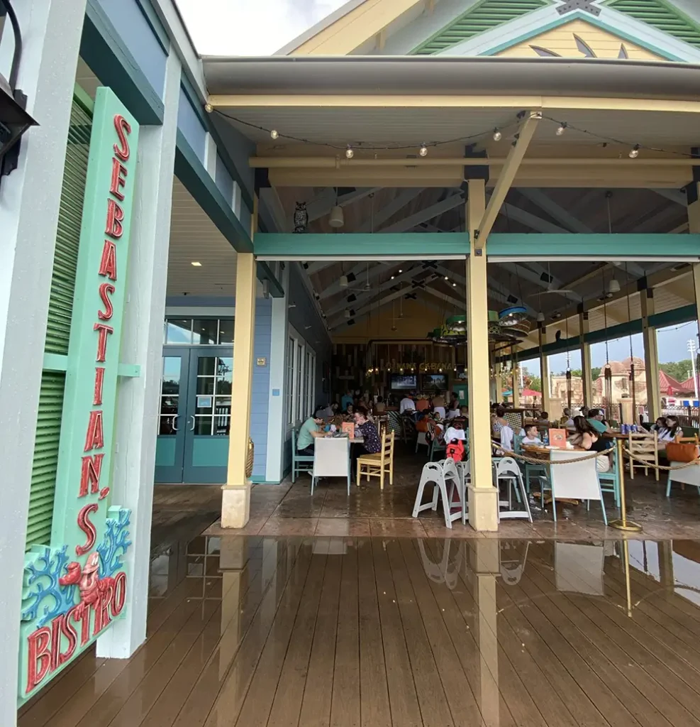 Entrance of Sebastians Bistro with people dining inside and outside, wooden deck reflecting the scene, and colorful decor giving a relaxed, beachside restaurant vibe. - Favorite Grampy Travels