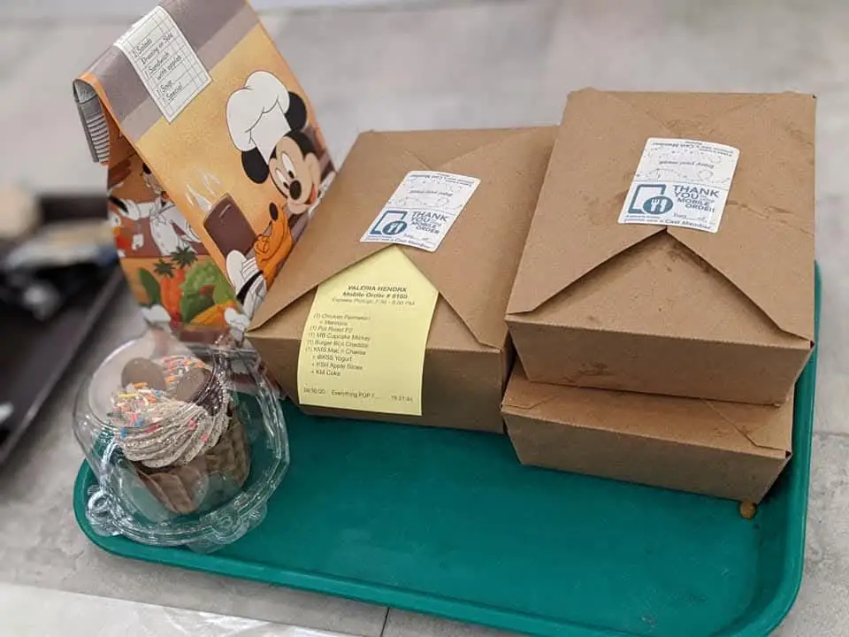Wdw-pop-century-resort-food-mobile-order - Favorite Grampy Travels a Turquoise Tray Holds Two Closed Brown Food Containers, a Cup with a Dessert Topped with Sprinkles, and a Disney-themed Paper Bag Featuring Mickey Mouse in a Chef Hat. - Favorite Grampy Travels - Favorite Grampy Travels 2026