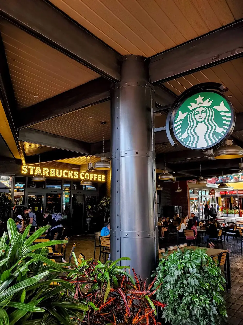 A Starbucks coffee shop in Orlando with outdoor seating under a covered patio and a prominent green siren logo sign. - Favorite Grampy Travels