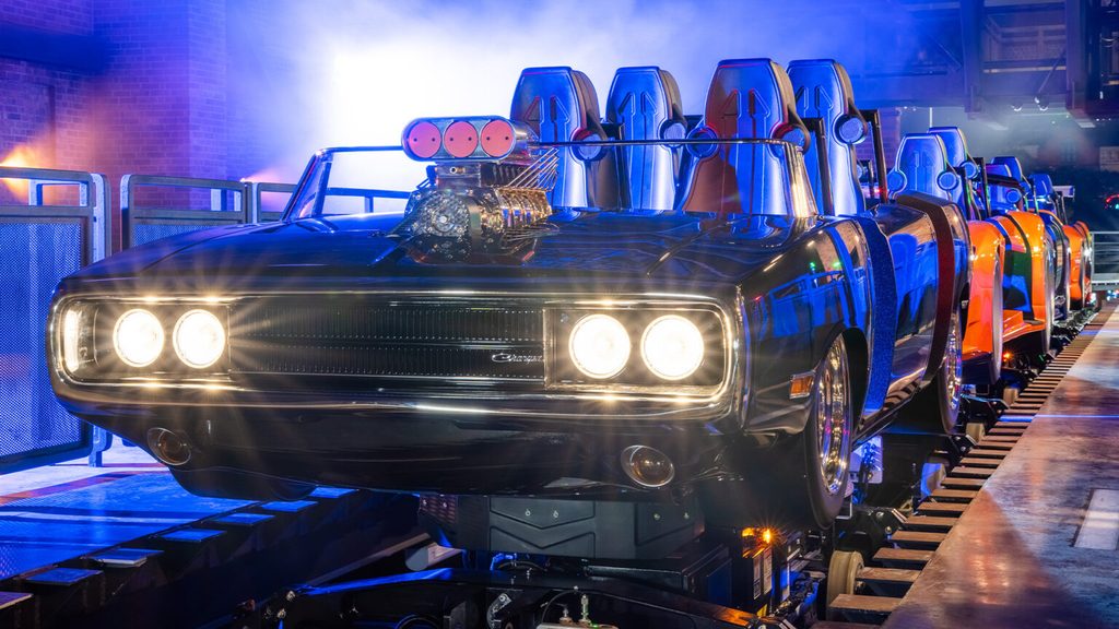 A roller coaster train designed like a black muscle car with headlights on, sits on tracks indoors with fog and dramatic lighting in the background, evoking the high-speed thrills of Universal’s Fast & Furious: Hollywood Drift. - Favorite Grampy Travels