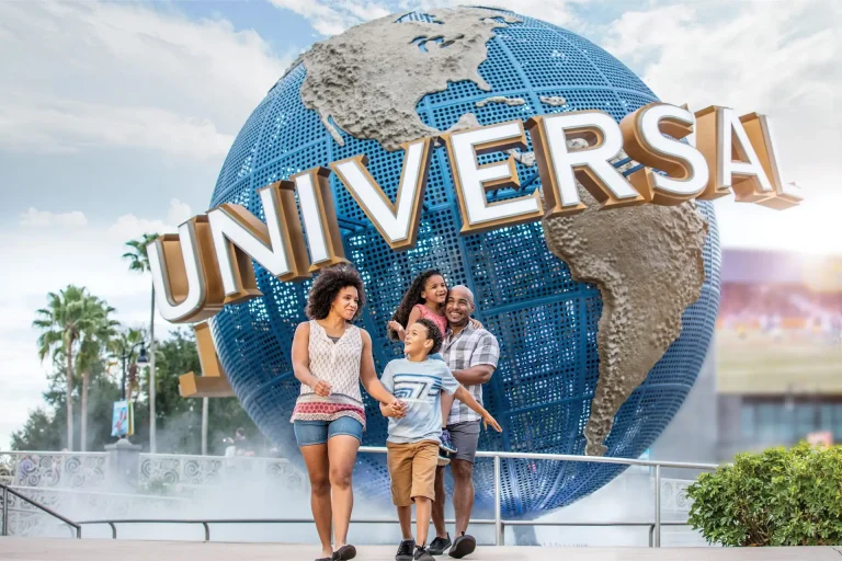 A family of four walks past the rotating Universal globe at the entrance to Universal Orlando Resort