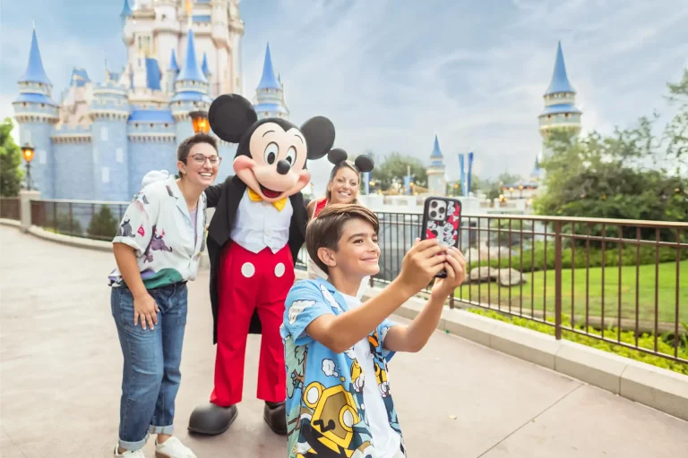 A boy takes a selfie with his family and Mickey Mouse in front of Cinderella Castle at Walt Disney World's Magic Kingdom