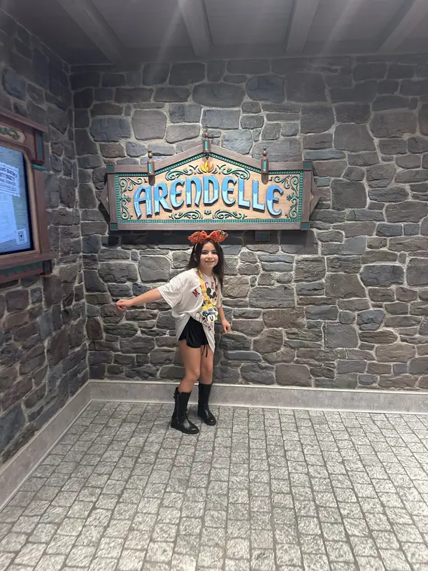 Avilene dancing under the Arendelle sign at the Frozen dining room on a Disney cruise
