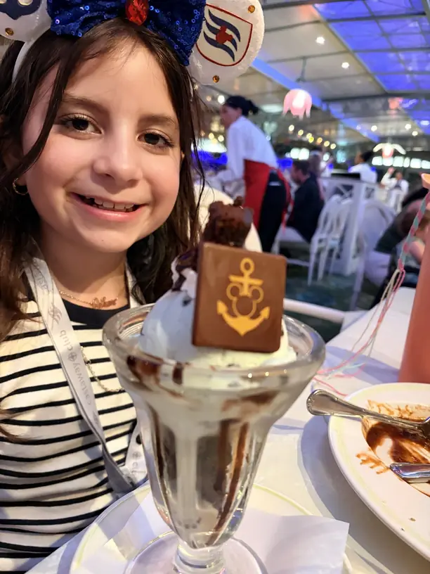 Avilene in cruise Mickey ears with an ice cream sundae topped with a Disney anchor chocolate