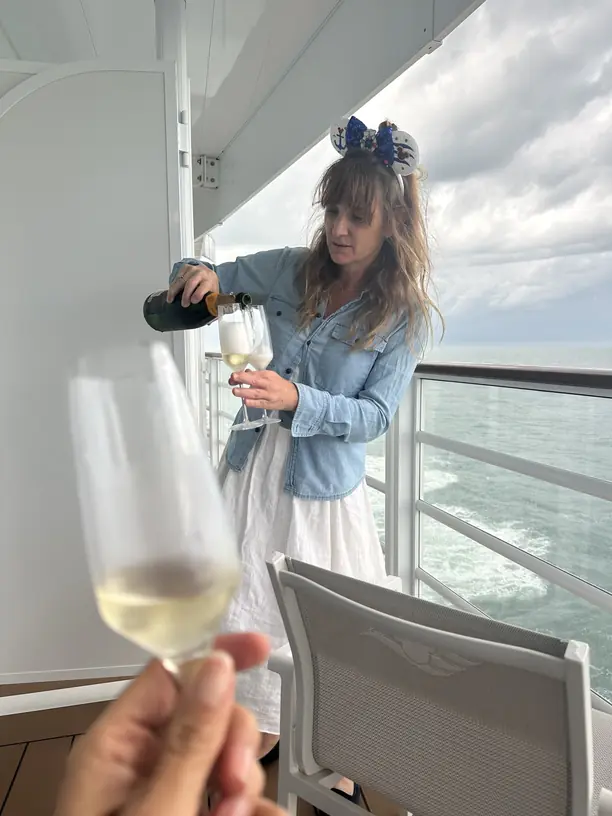 Pouring champagne on a Disney cruise verandah at sea