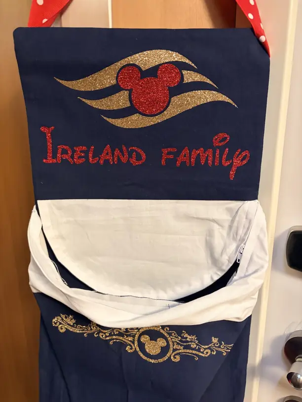 A navy fish extender with a glitter Disney Cruise Line logo hanging on a stateroom door