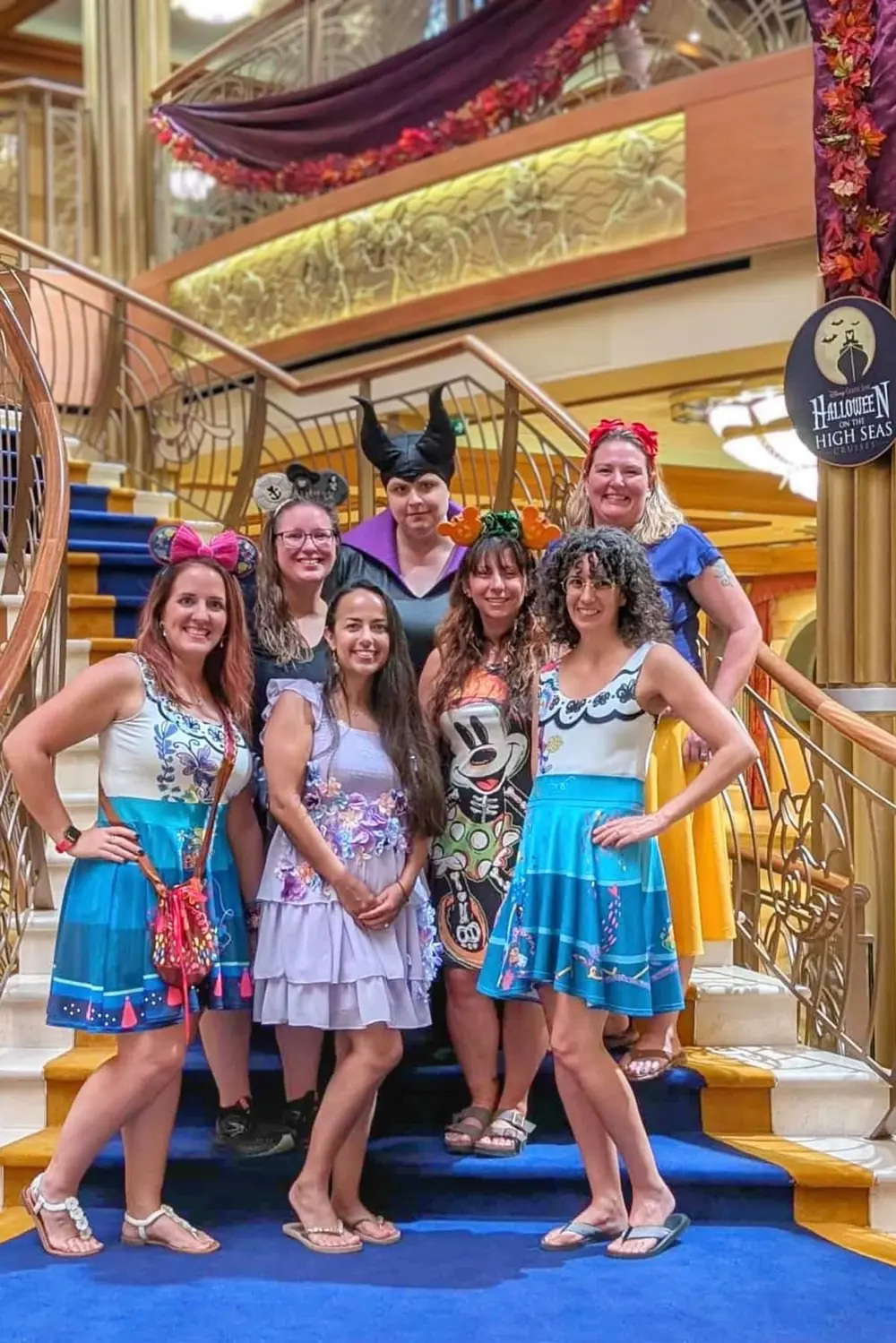 A group of friends in costume on the grand staircase in the atrium during Halloween on the High Seas