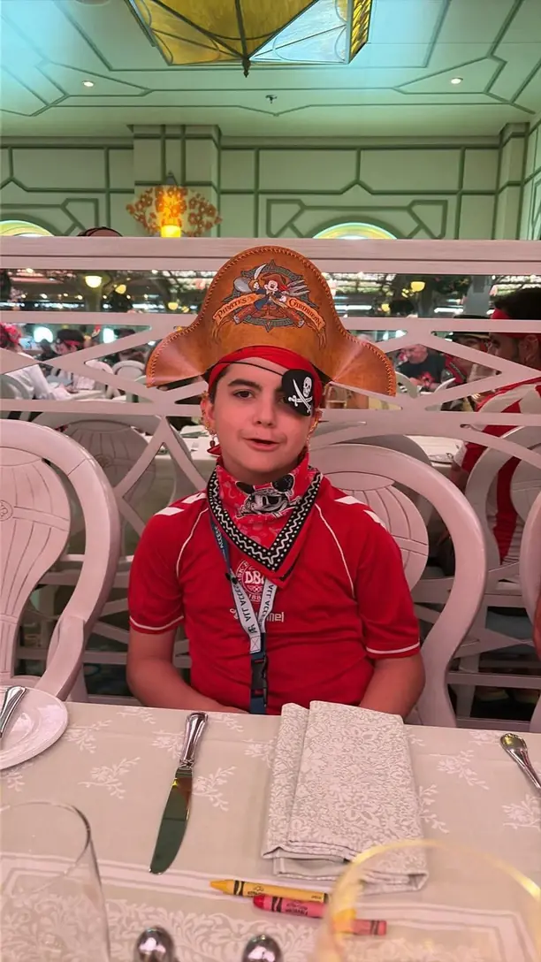 Jake in a pirate hat, eyepatch and bandana at Pirate Night dinner on a Disney cruise