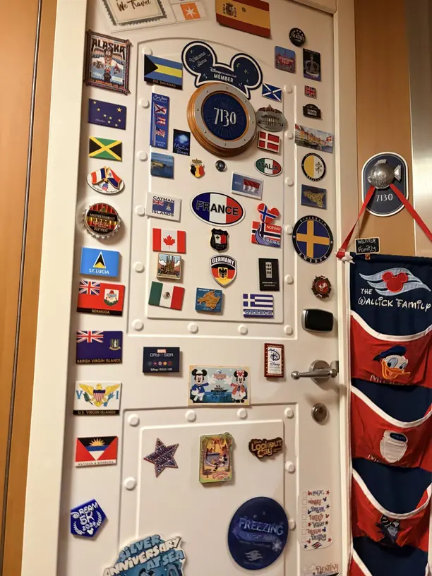 A Disney cruise stateroom door covered in country flag and cruise magnets
