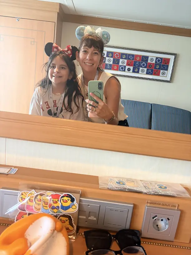 Nicole and Avilene in Mickey ears taking a mirror selfie in their Disney cruise stateroom