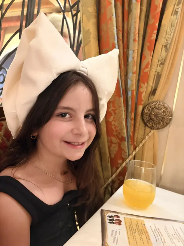 Avilene wearing a napkin folded into a bow at dinner on a Disney cruise
